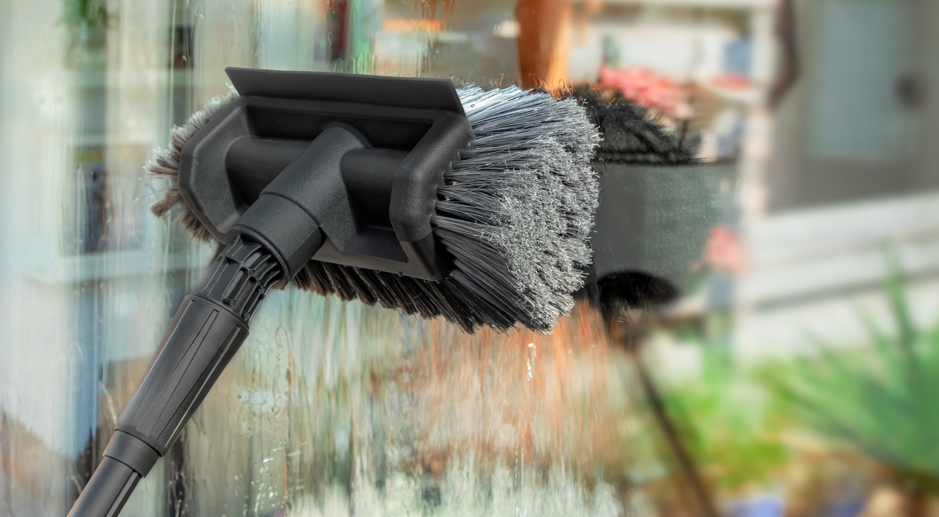 Raam schoonmaken met een VONROC wasborstel.